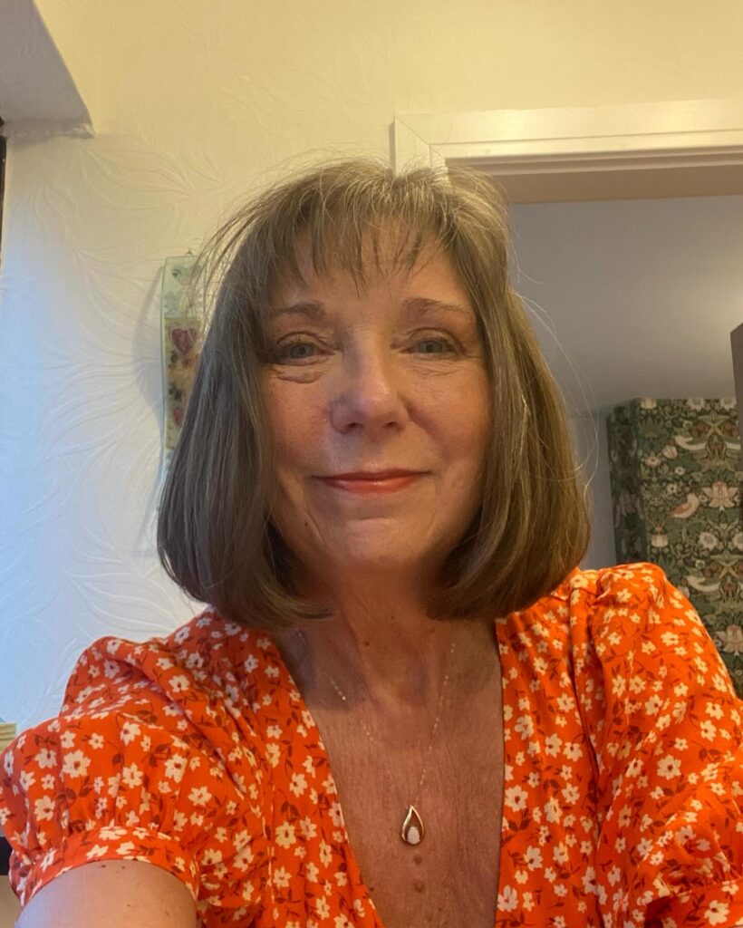 A woman with a chin-length, rounded ash-brown bob and soft wispy bangs.