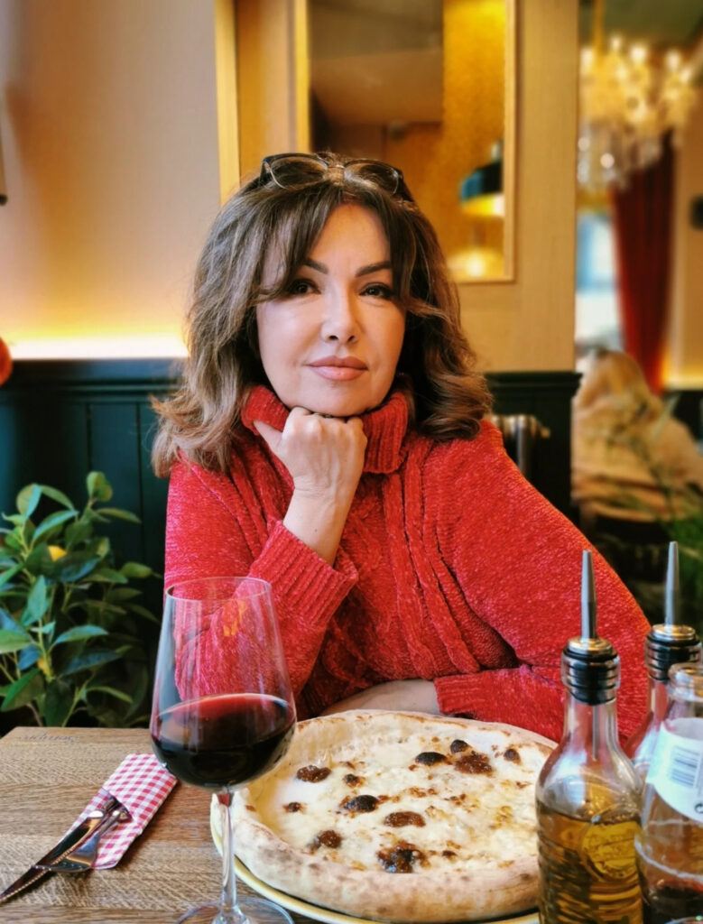 A woman over 60 with a shoulder-length brunette lob featuring voluminous waves and curtain bangs.