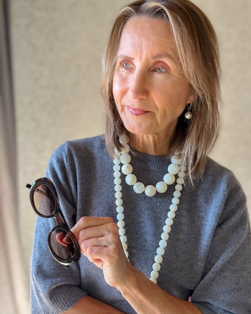 A woman over 60 with a sleek collarbone-length lob featuring honey blonde highlights and a side part.