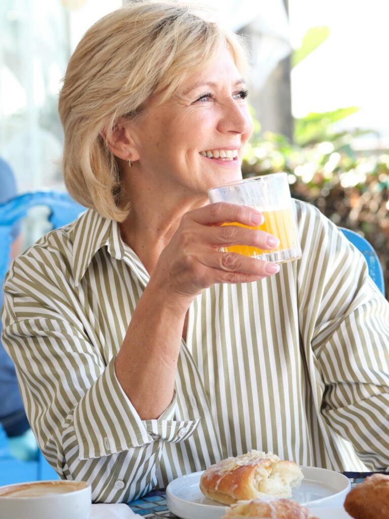 A smiling woman over 60 with a layered honey blonde bob styled with a swept-back finish.