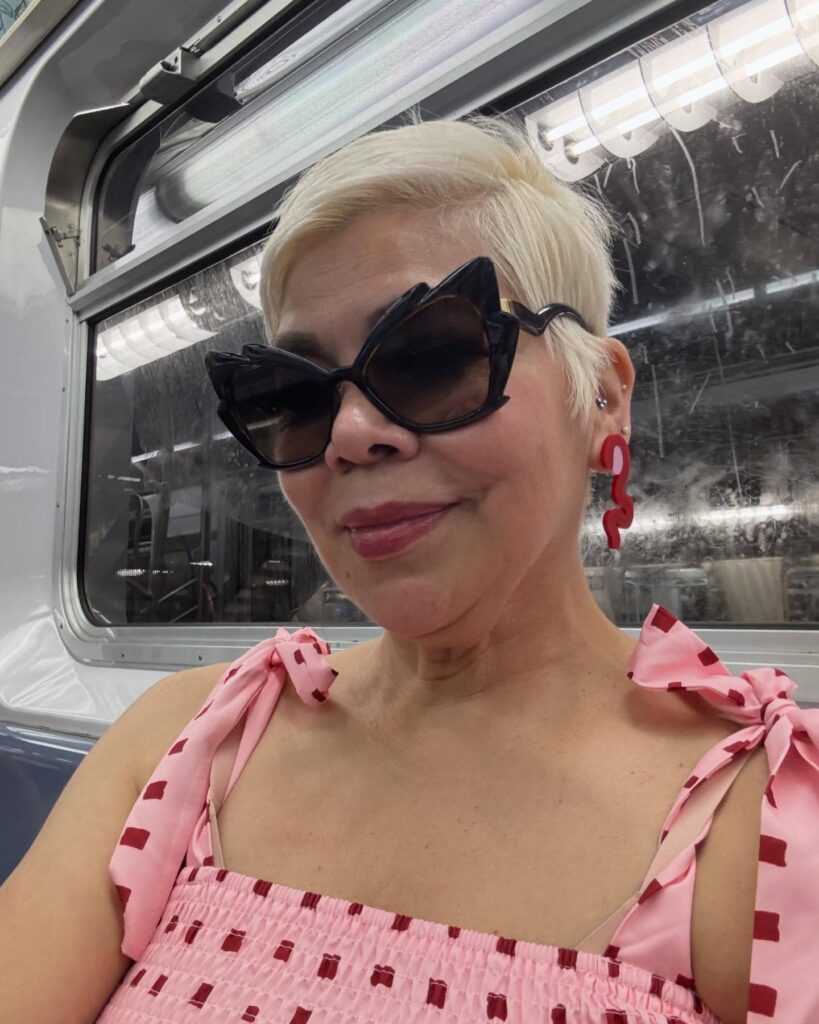 A woman with dramatic black cat-eye sunglasses wearing an icy blonde tapered pixie cut with side-swept textured layers.