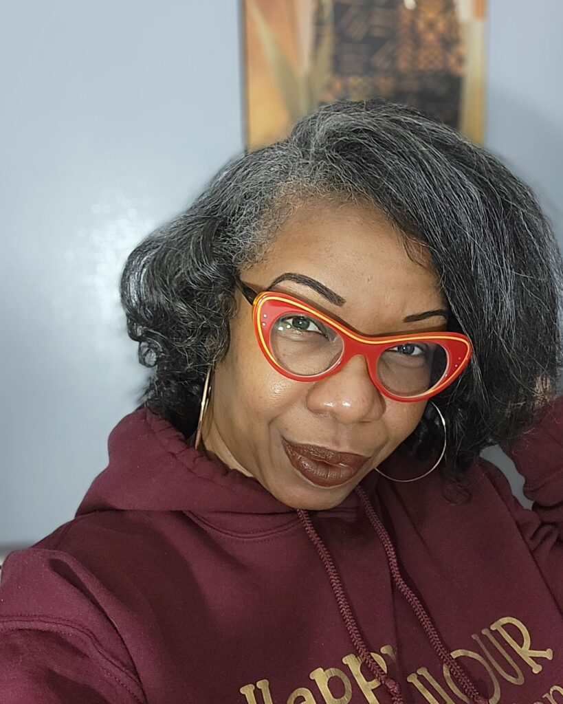 A Black woman over 60 wearing a voluminous silver and grey bob styled with a deep side part and soft waves.