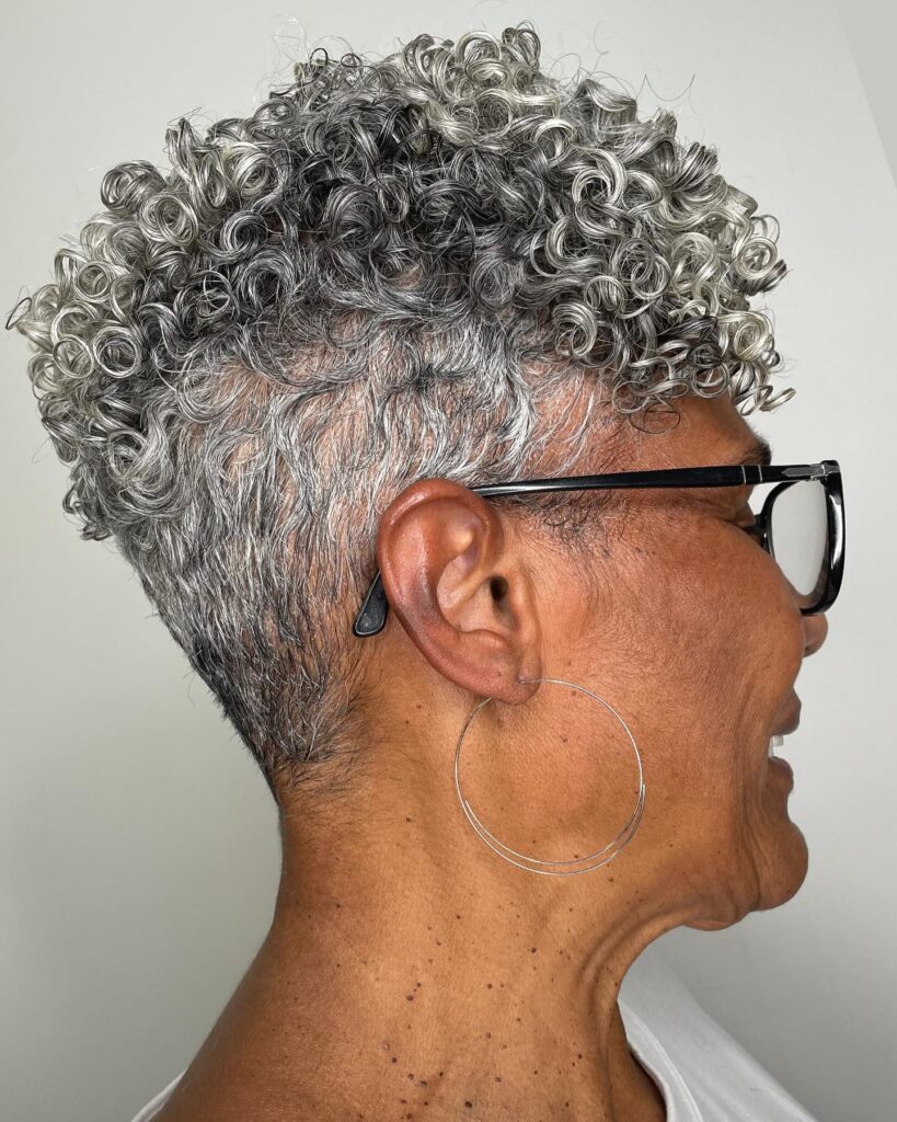 A profile view of an older Black woman with a short tapered silver pixie cut featuring tight, defined curls on top.