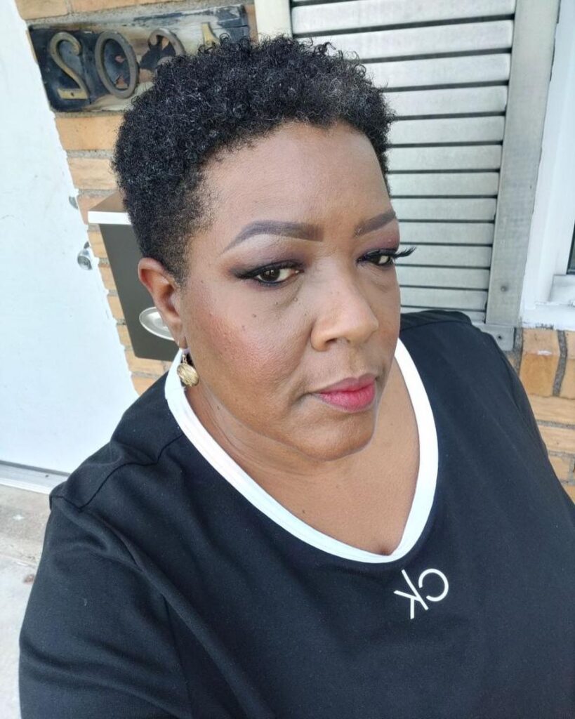 A Black woman over 60 posing with a short and neat, natural, tapered, teeny-weeny afro with hints of grey.