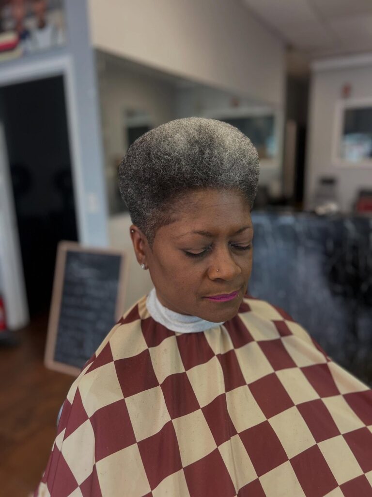 An older Black woman with a tall and perfectly rounded salt-and-pepper teardrop-shaped afro.