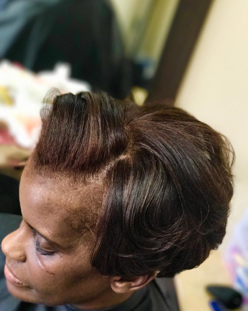 A close-up side view of an older Black woman with a sleek, dark brown swept-back hairstyle featuring soft, curved layers and mahogany highlights.