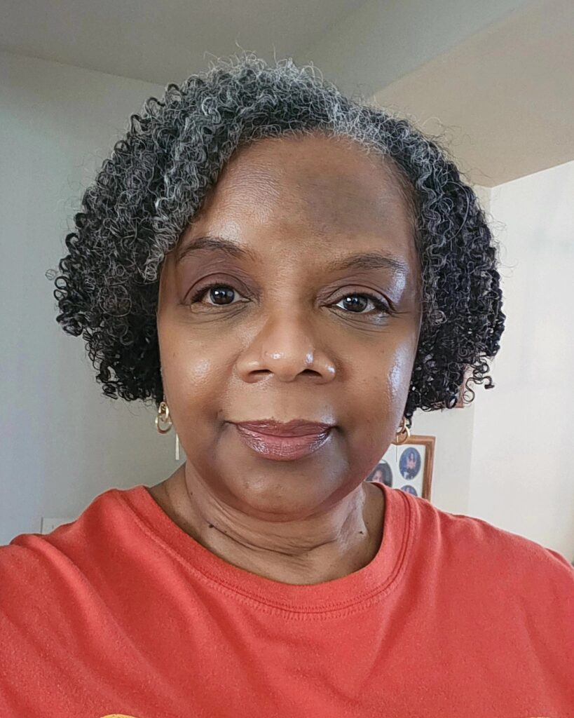 A Black woman over 60 with a neck-length hairstyle of tight salt-and-pepper micro coils styled with a side-swept look.