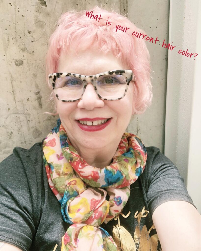 A woman with a textured pink pixie cut and soft wavy bangs.