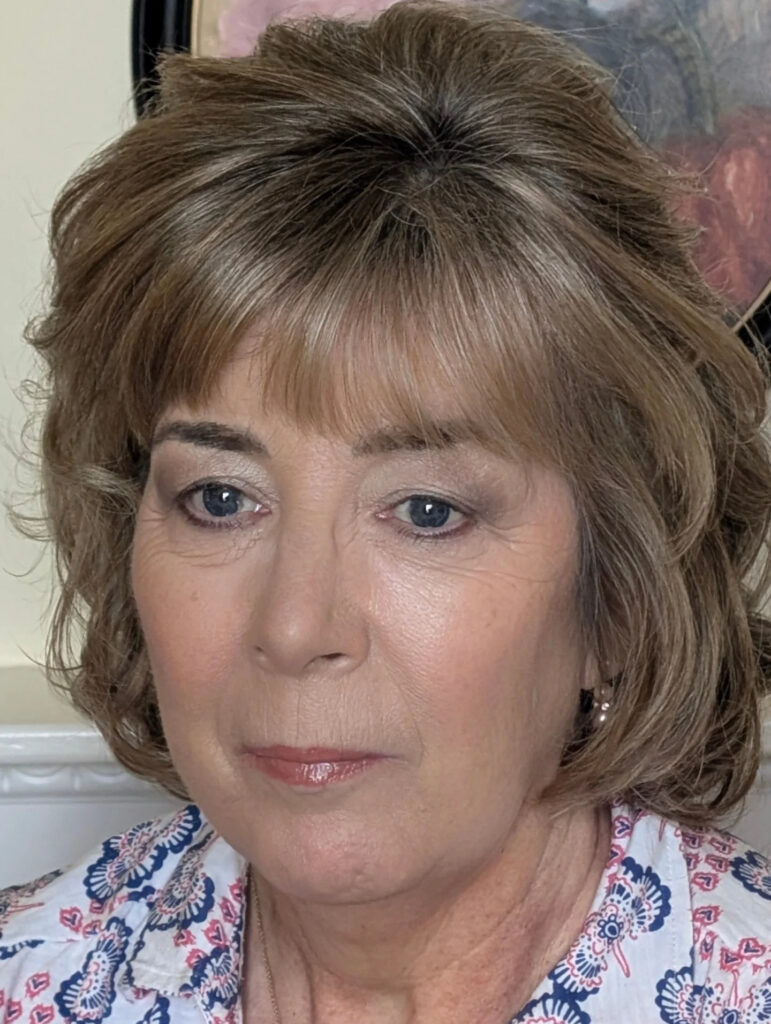 A woman with a layered toffee-blonde bob and a full wispy fringe.