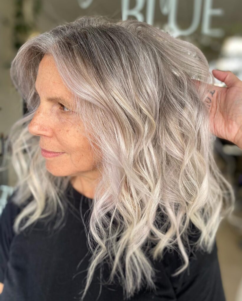 A woman with shoulder-length ash blonde hair styled in loose beachy waves.