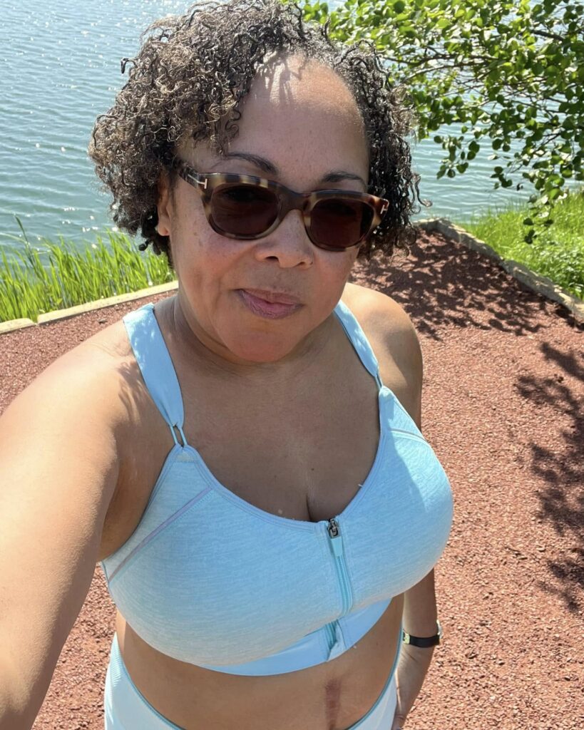 A woman outdoors wearing a shoulder-length curly bob in a dark brown shade with natural texture.
