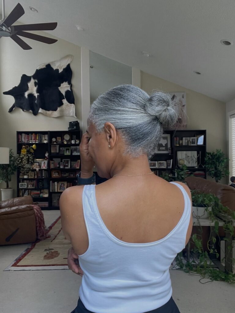 A woman over 60 with her salt-and-pepper hair pulled back into a neat low bun.