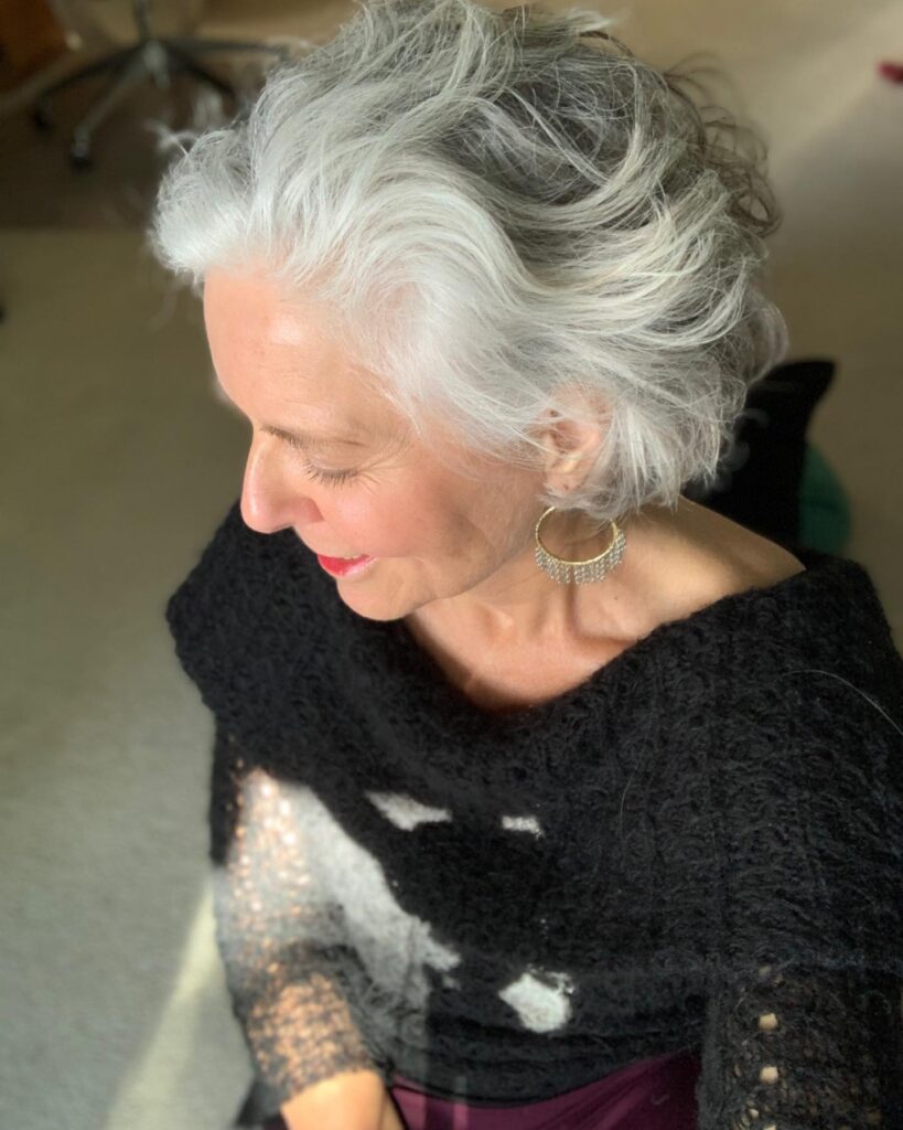 A woman viewed from above with a short silver bob styled in soft, swept-back layers.