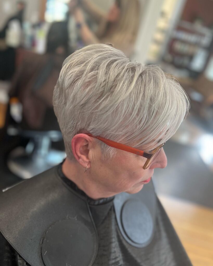 A woman with a short side-swept pixie cut in a light ash blonde color and wispy layers.