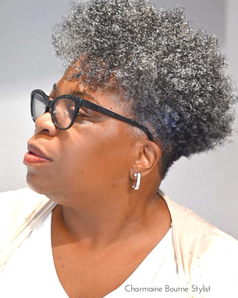 A woman over sixty with a voluminous tapered afro featuring tight salt-and-pepper curls.