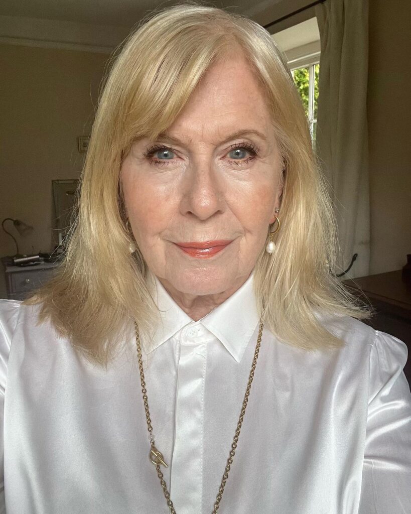A woman over sixty with a sleek shoulder-length pale blonde lob and soft side-swept bangs.