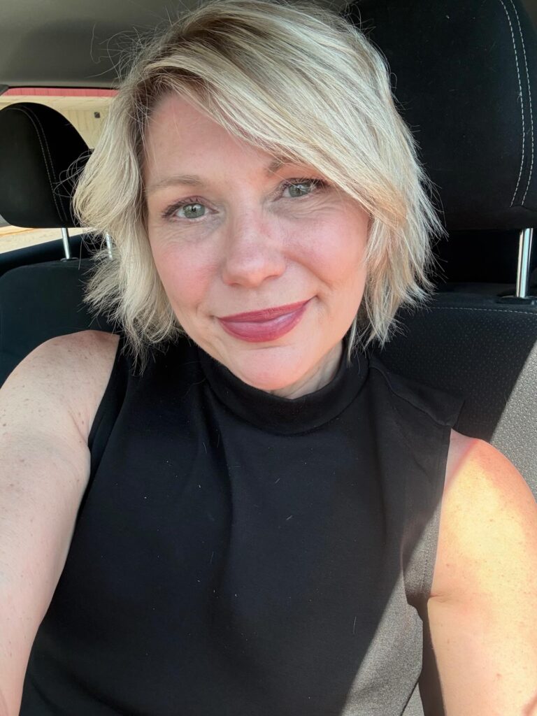A woman with a jaw-length ash blonde bob featuring choppy layers and a side-swept style.