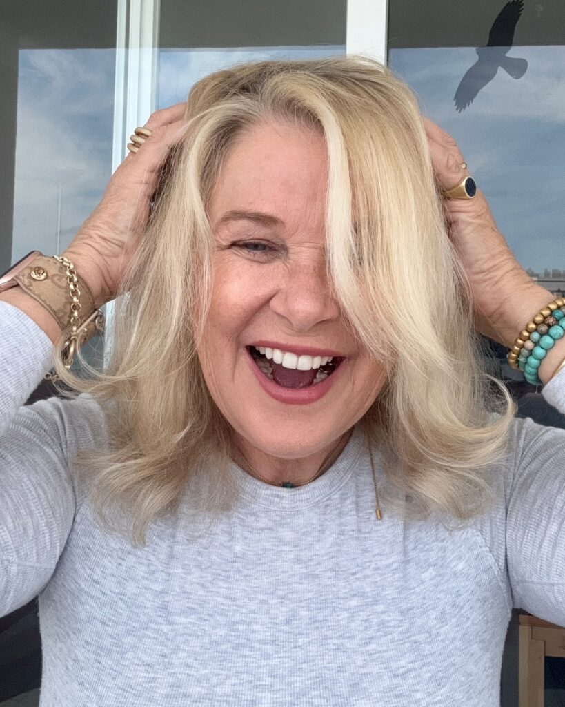 A smiling woman over sixty with a collarbone-length champagne-blonde lob featuring soft layers and flipped-out ends.