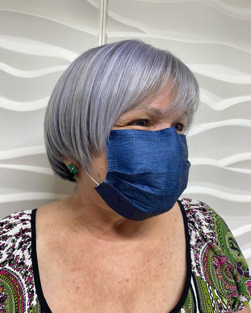 A woman with a straight chin-length bob featuring a blend of lavender and silver hair colors and soft bangs.