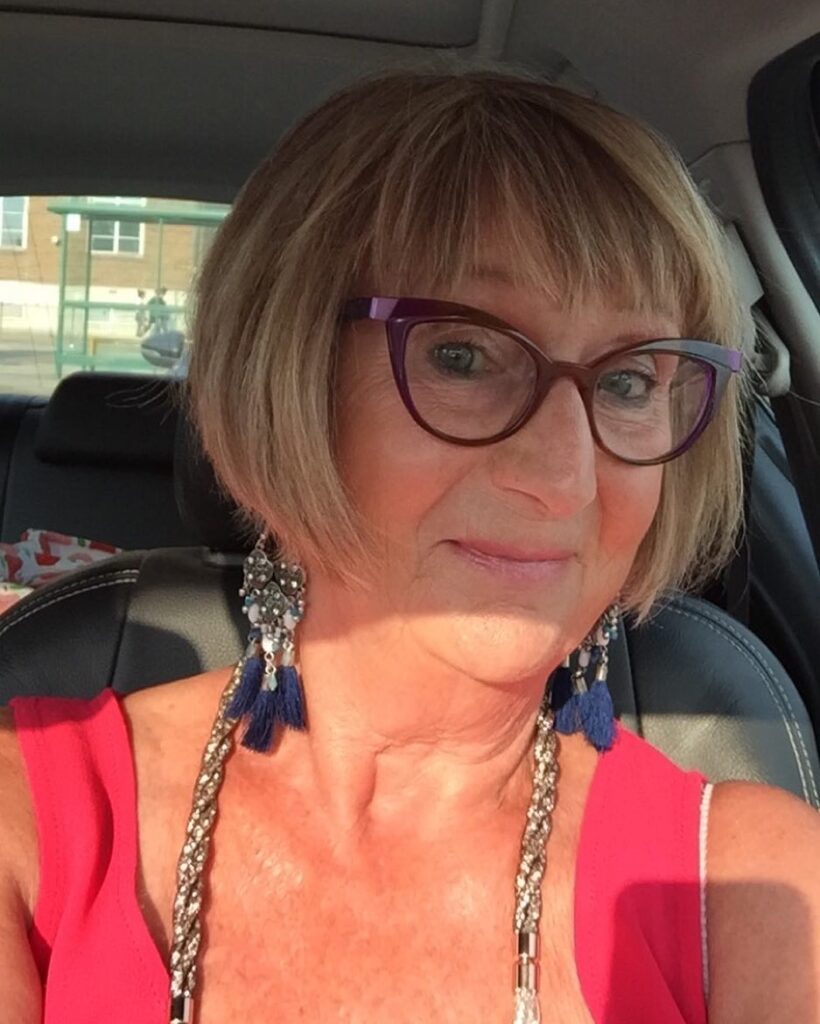 A side profile of a woman with a sleek, rounded chin-length ash brown bob featuring smooth texture and subtle highlights.