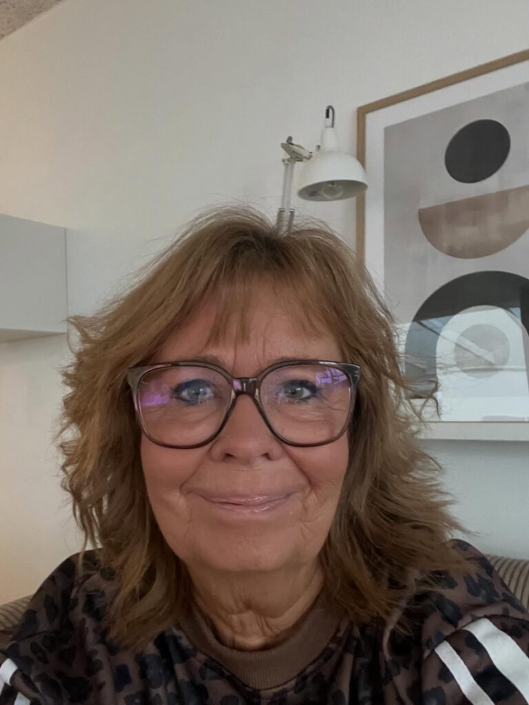 A woman over sixty with a square face shape wearing a shoulder-length caramel brown shaggy haircut with choppy layers and thin bangs.