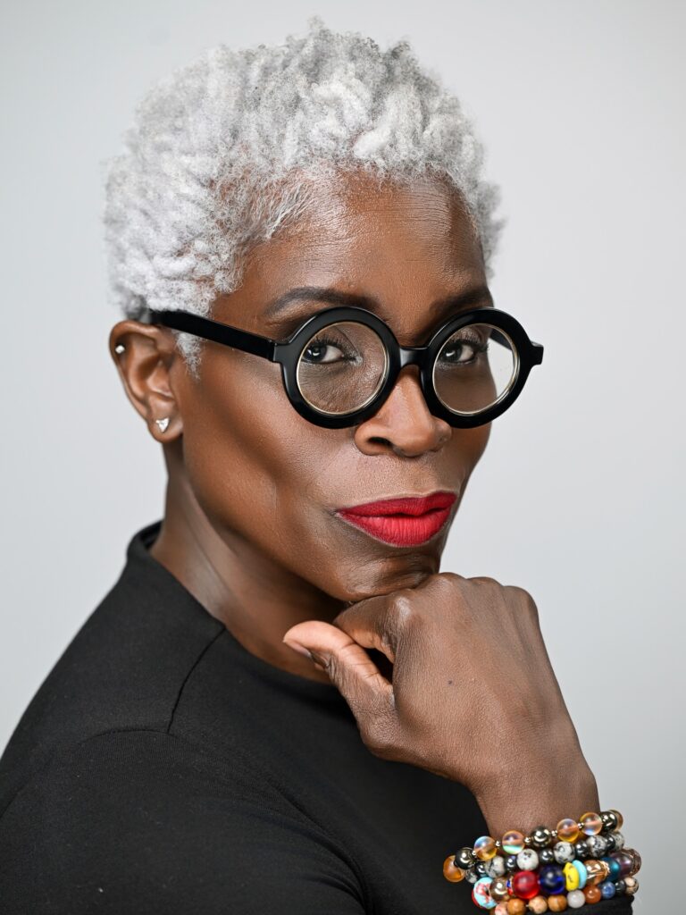 A woman with a bright silver tapered afro featuring short sides and a voluminous, textured top.