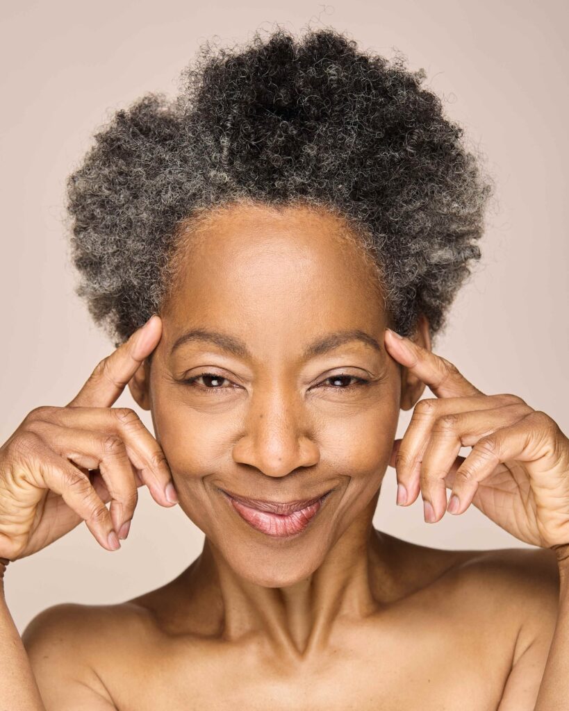 A smiling woman with a natural salt-and-pepper teeny-weeny afro that has soft and well-defined silver coils.