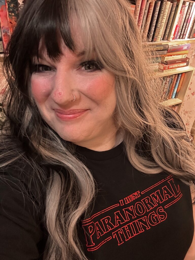 A woman over 60 with long wavy hair featuring a split-dye color of black and silver with a full fringe.