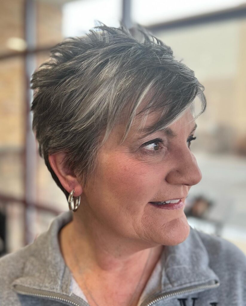 Short salt and pepper pixie haircut with layered volume on top.