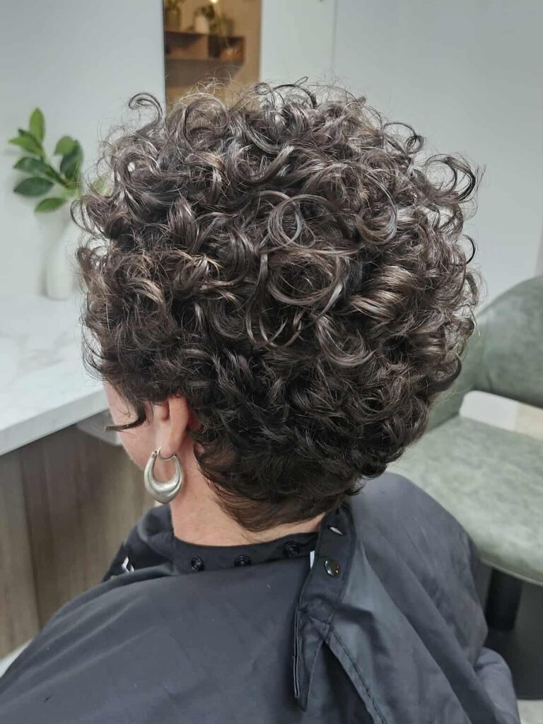 Short curly pixie haircut with natural volume and defined texture.