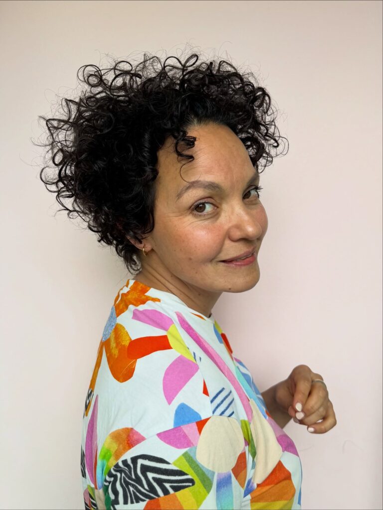 Short curly pixie haircut with a rounded shape and soft layers.