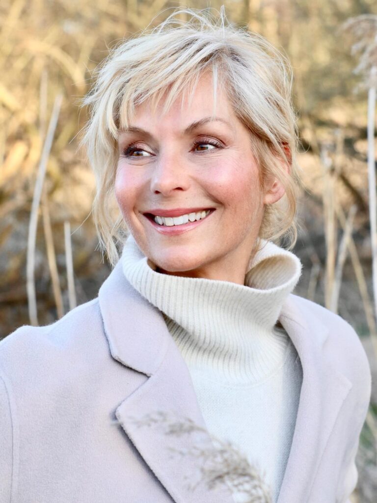 Ear-length blonde pixie with soft layers and a side swept front.