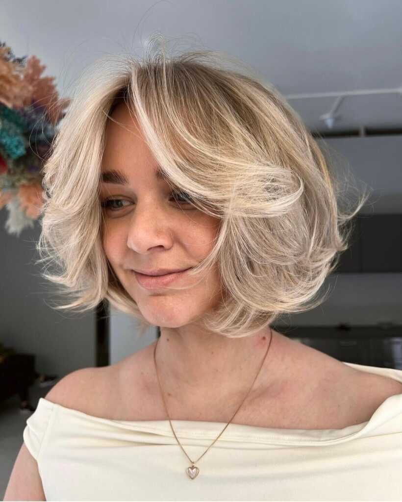 Platinum blonde layered bob with voluminous flipped layers and rounded shape.