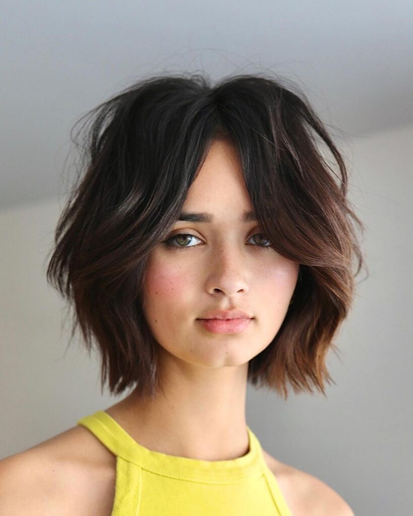 Textured shaggy bob with dark layered waves and soft curtain framing pieces.