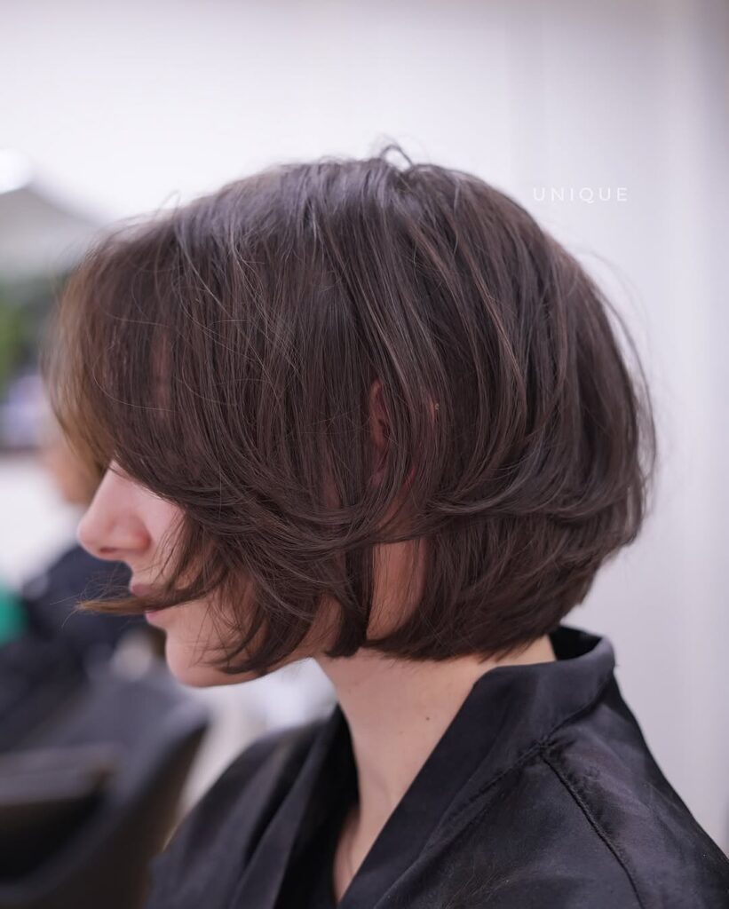 Soft brunette layered bob with curtain fringe and rounded volume through the sides.