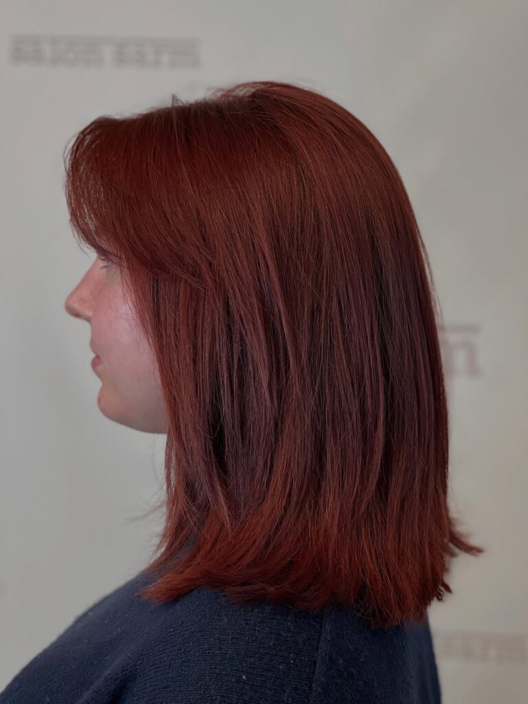 Straight auburn long bob with soft layers and lightly flicked ends.