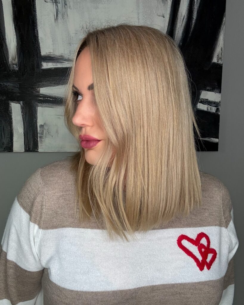 Straight shoulder length vanilla blonde long bob with a blunt cut and center part.