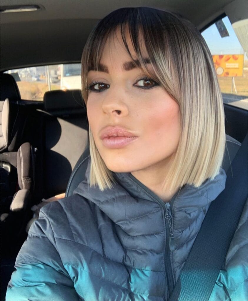 Blunt blonde long bob with defined curtain bangs and sleek straight edges.