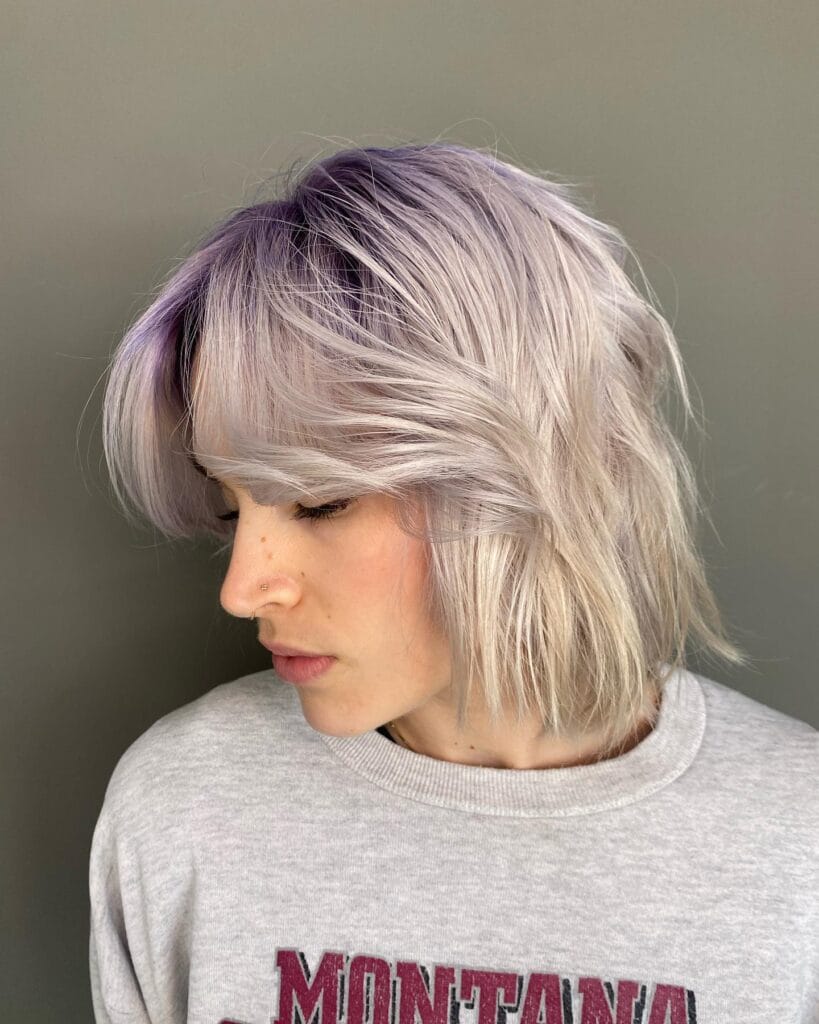 Textured platinum long bob with soft feathered curtain bangs and airy layers.