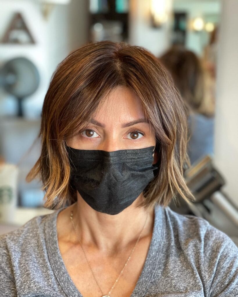 Soft brown long bob with blended curtain bangs and light layered movement.