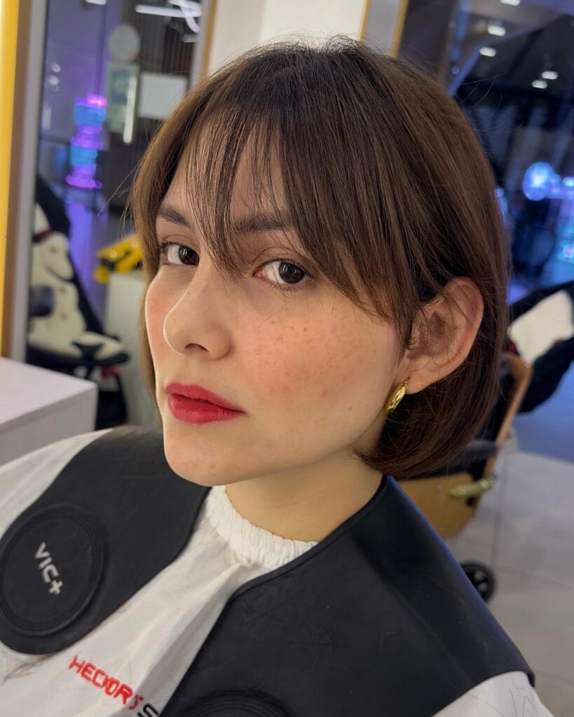 Chin length sleek long bob with softly parted curtain bangs and straight finish.