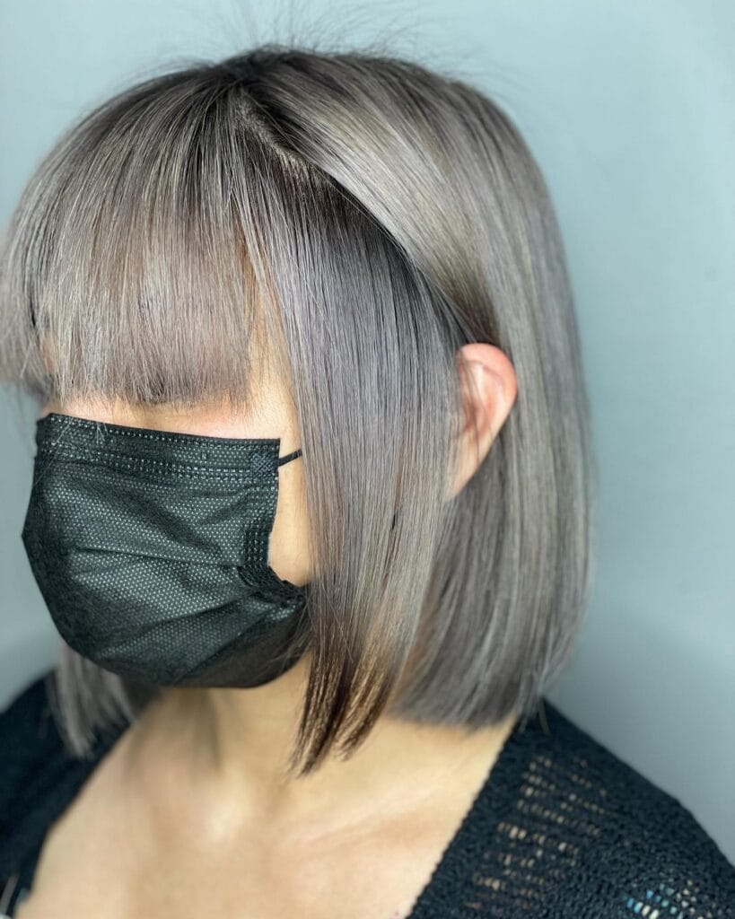 Sleek silver long bob with blunt curtain bangs and straight polished finish.