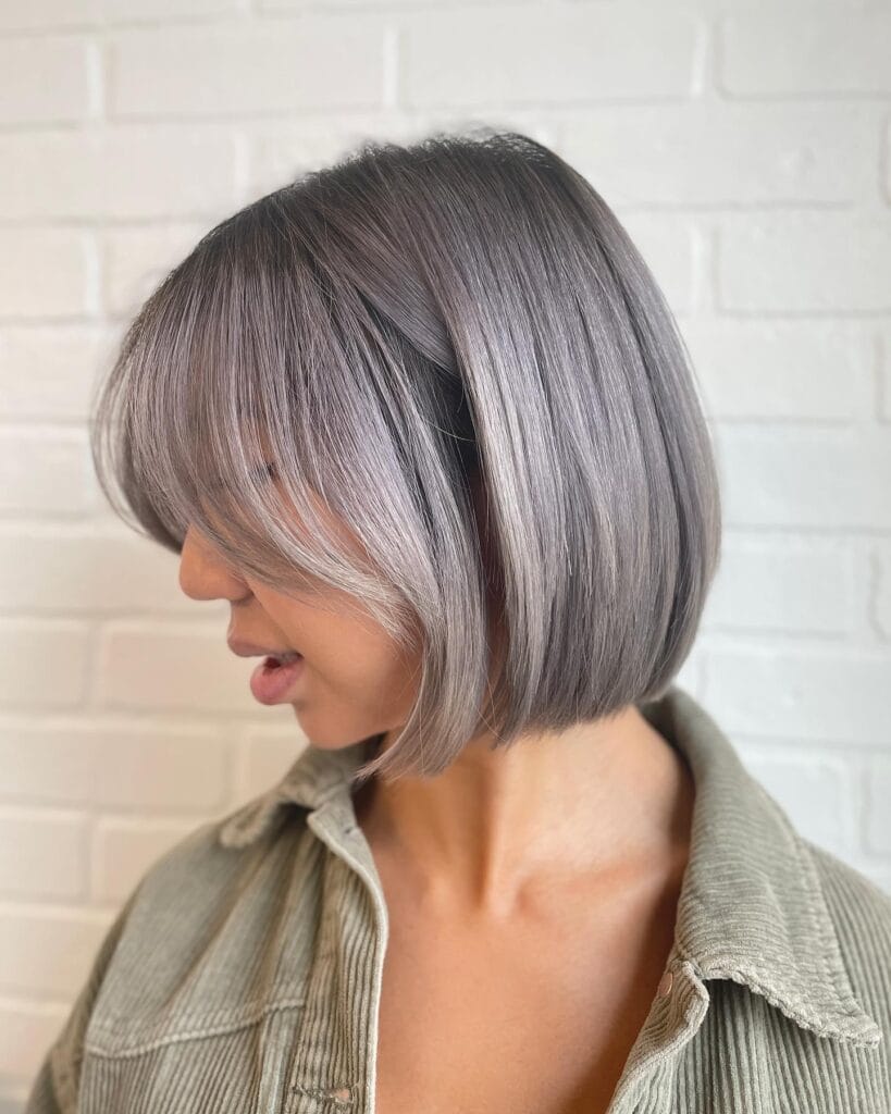 Sleek angled gray long bob with curtain bangs and smooth straight finish.