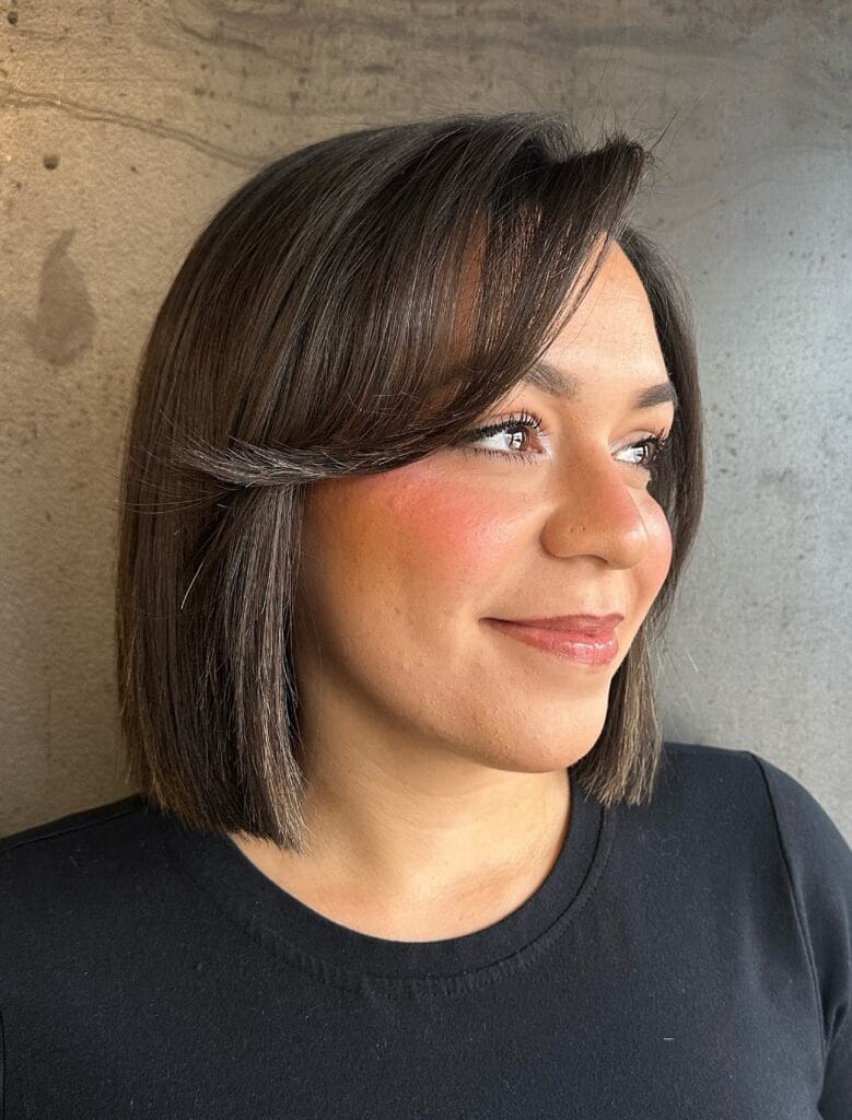 Long brunette bob with soft layers and feathered curtain bangs parted in the middle.