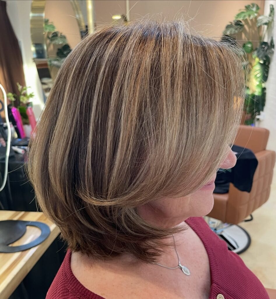 Layered long bob with voluminous curtain bangs and soft highlighted dimension.
