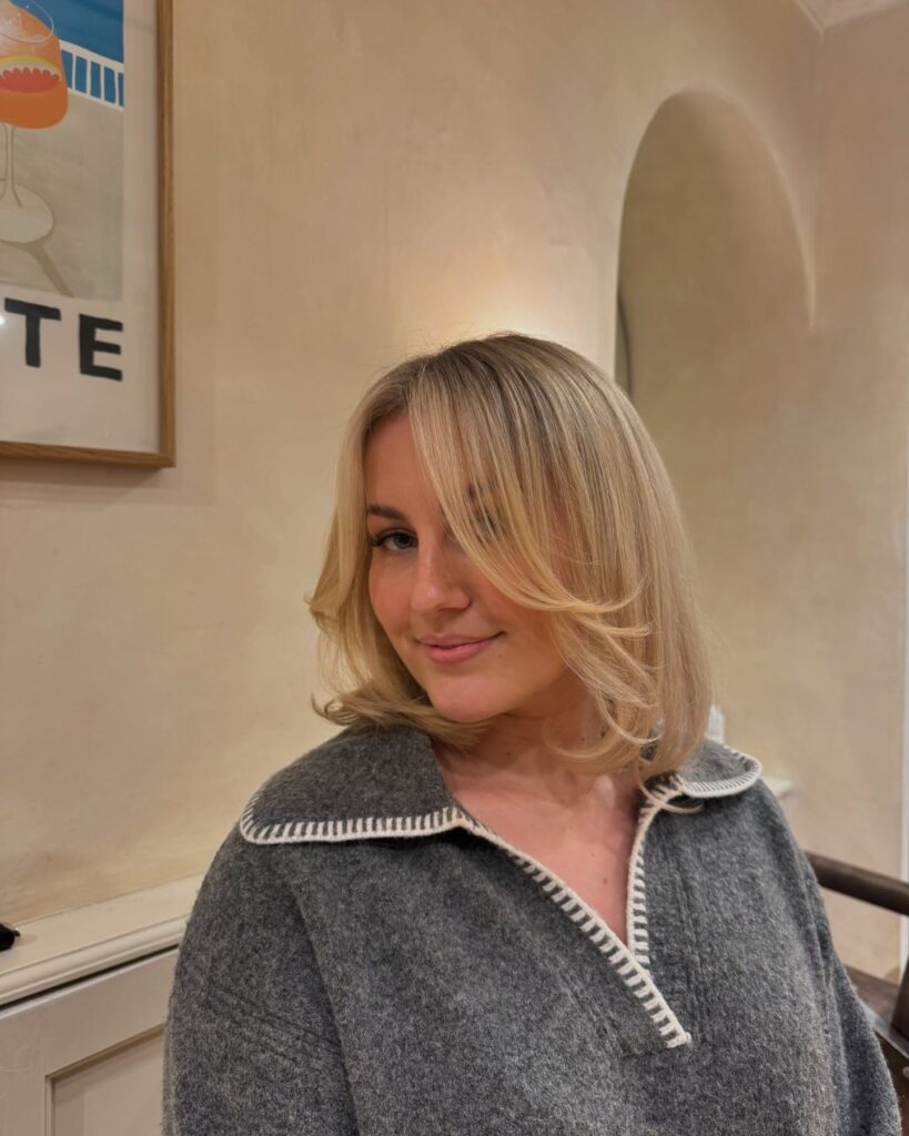 Blonde long bob with smooth styling and softly flipped ends at shoulder length.