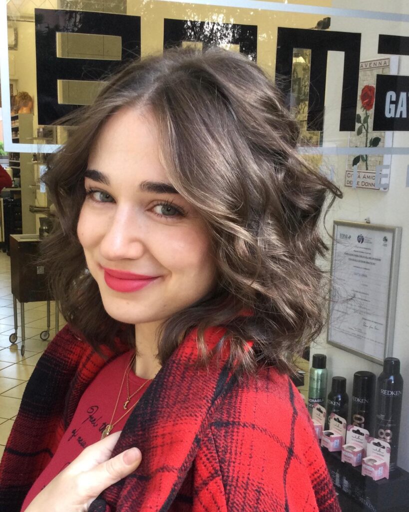 Soft wavy brown long bob with light layers and natural volume around the shoulders.