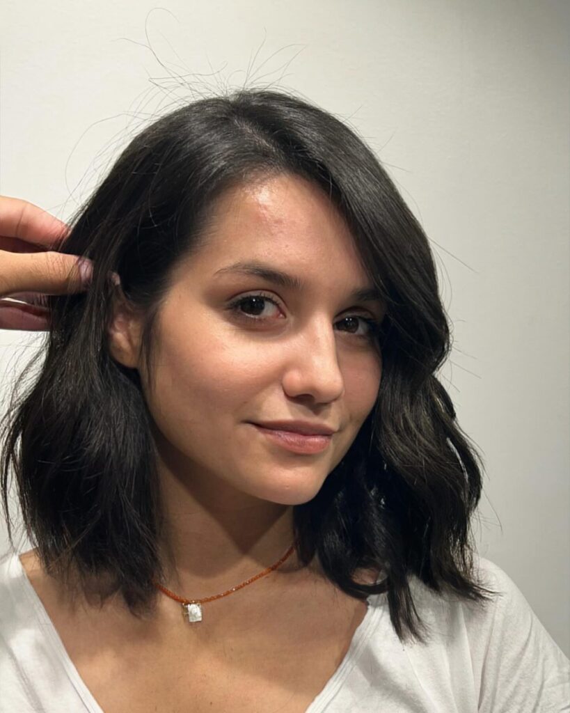 Dark wavy long bob with a side swept part and soft natural texture.