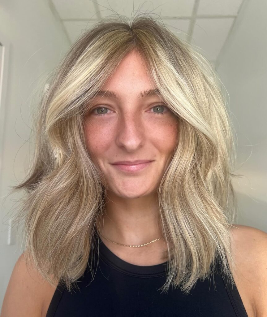 Textured sandy blonde lob with soft layers and natural volume around the crown.