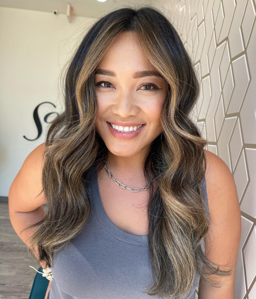 Brunette long bob with soft waves and face framing blonde highlights around the front.